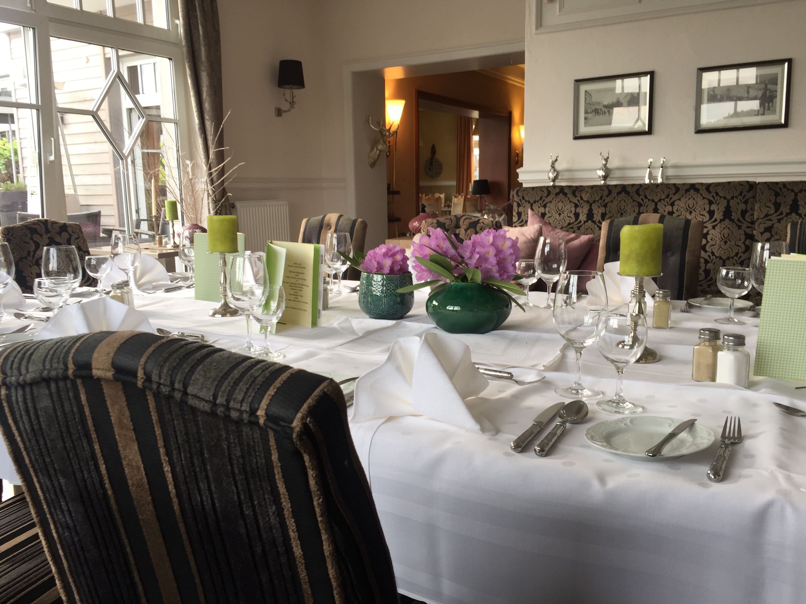 Une salle à manger avec une table mise pour le repas, agrémentée d’un vase de fleurs, de bougies et d’un mur orné de motifs.