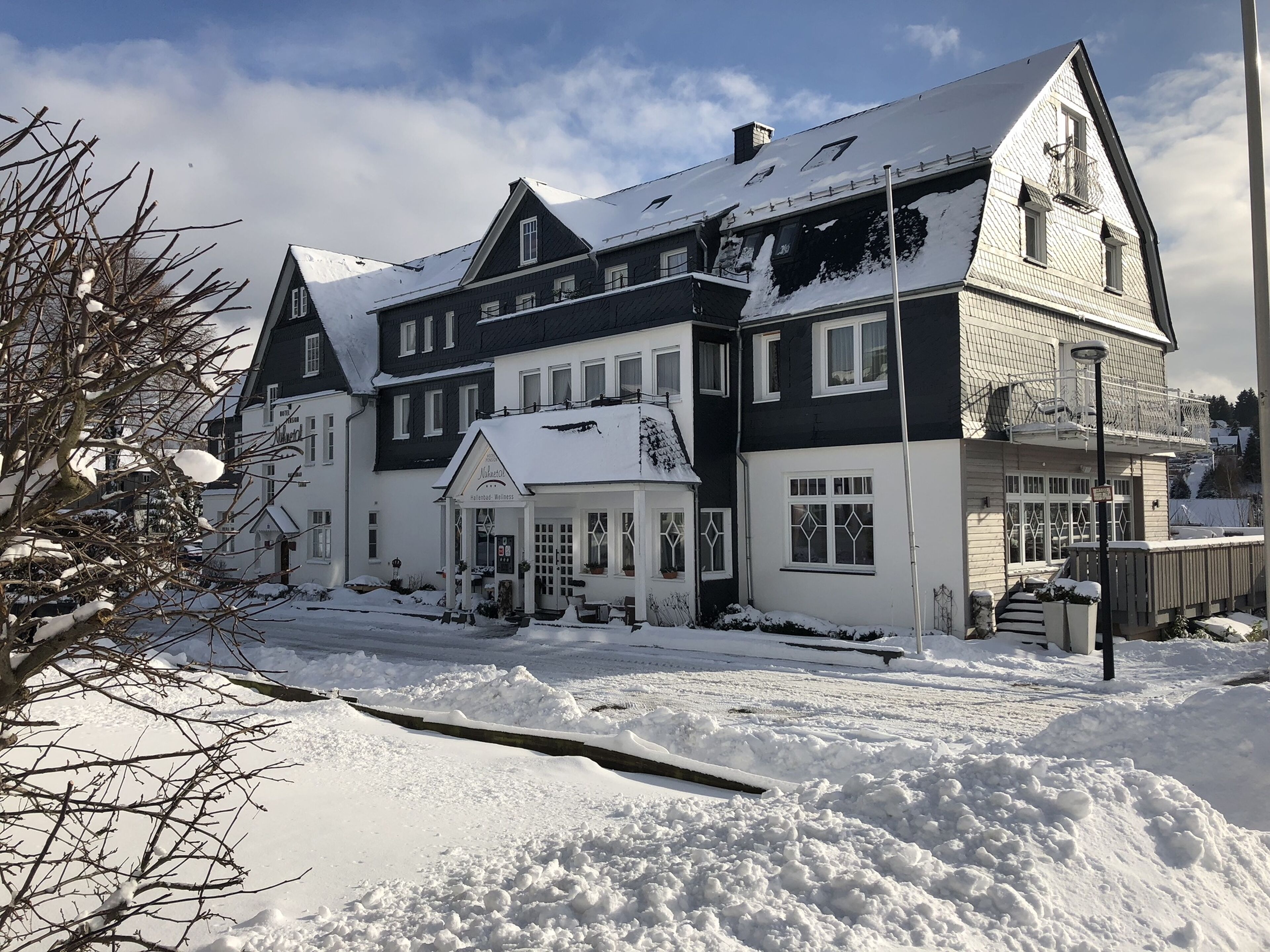 Um edifício de dois andares com telhado coberto de neve e um pequeno alpendre.