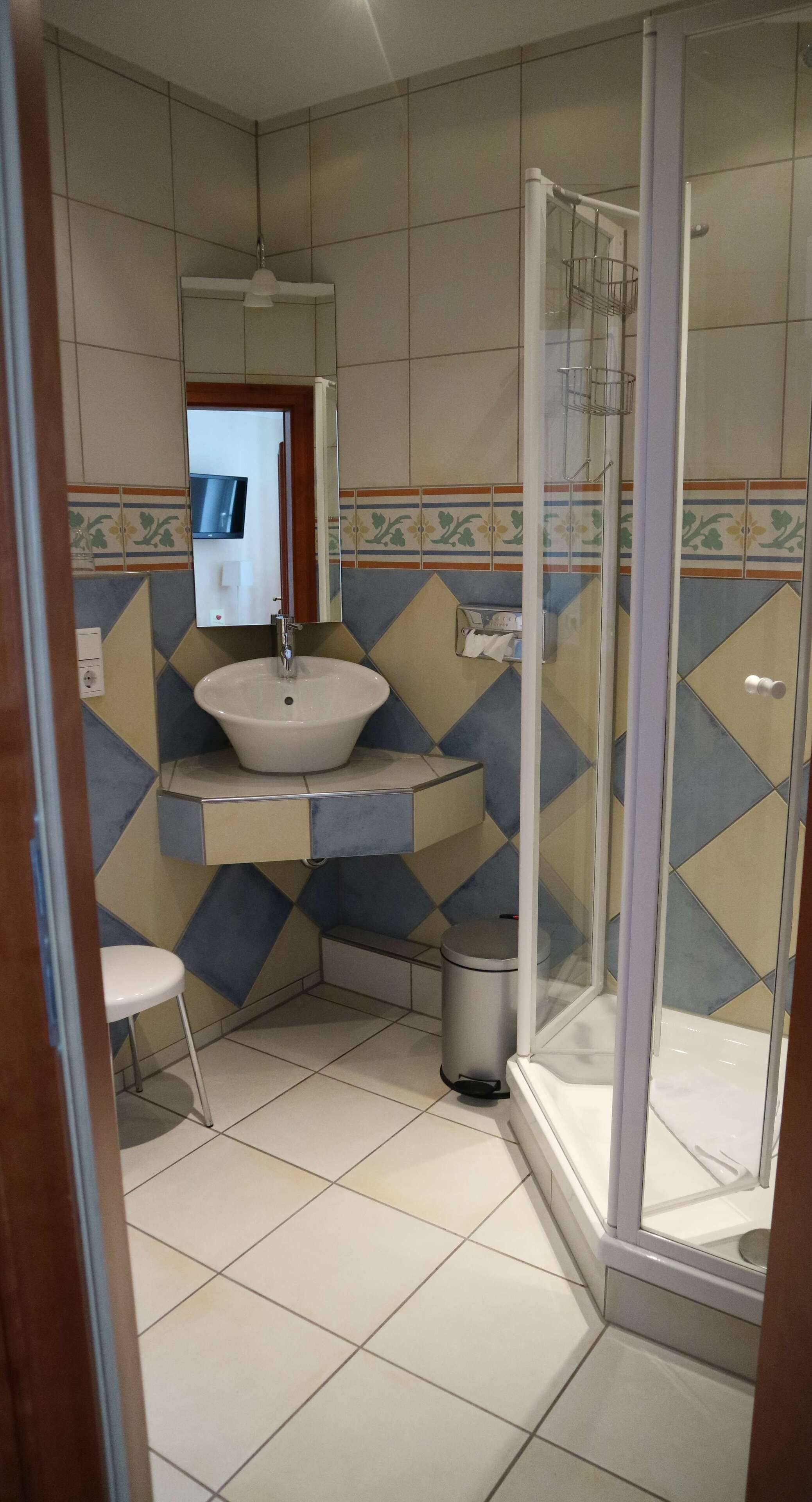 A bathroom with a sink, mirror, toilet, and shower.