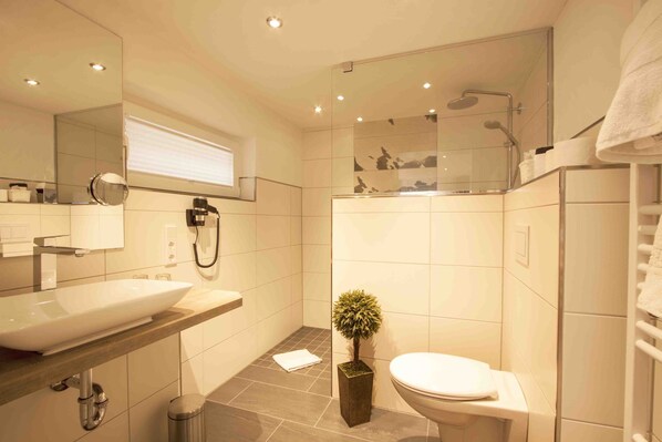 A modern bathroom with a large sink, toilet, and shower area.