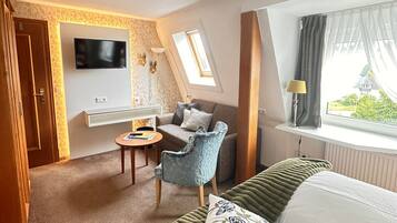 Ein Hotelzimmer mit Bett, Schreibtisch, Stuhl, Fernseher und einem Fenster mit Vorhängen.