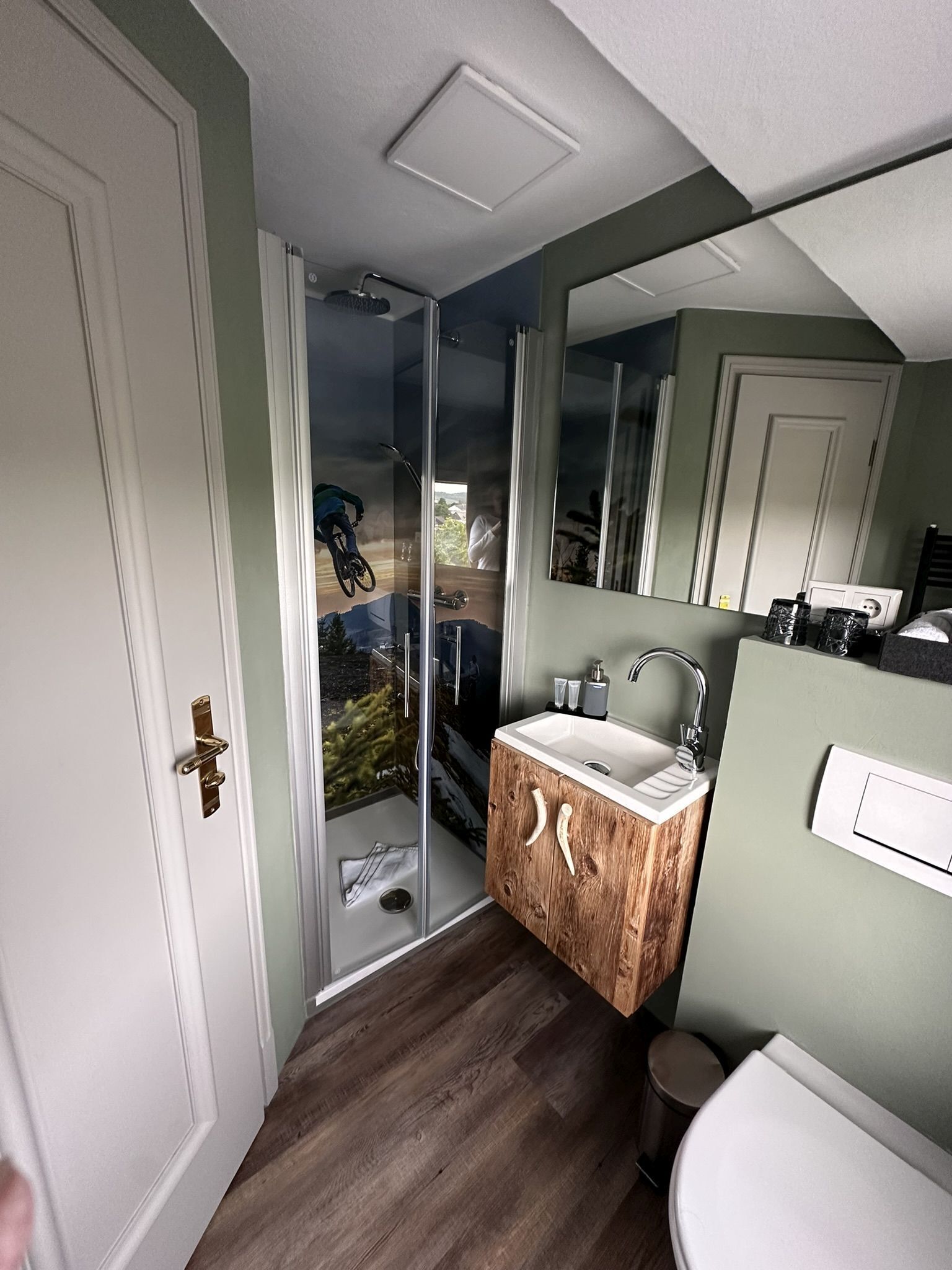 A bathroom with a wooden vanity, a white sink, a mirror, and a glass shower enclosure.