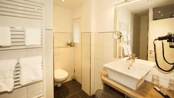 Une salle de bain moderne avec un lavabo blanc, un miroir et un porte-serviettes.