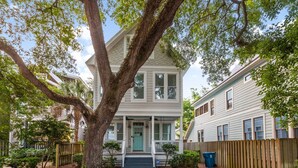 A two-story house with a front porch, a large tree, and a wooden fence. - Awesome 4 bed/3.5 bath pup-friendly South End Home (Saint Simons Island)