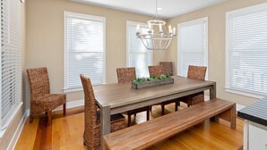 A dining area with a wooden table, four wicker chairs, a bench, and a chandelier. - Awesome 4 bed/3.5 bath pup-friendly South End Home (Saint Simons Island)