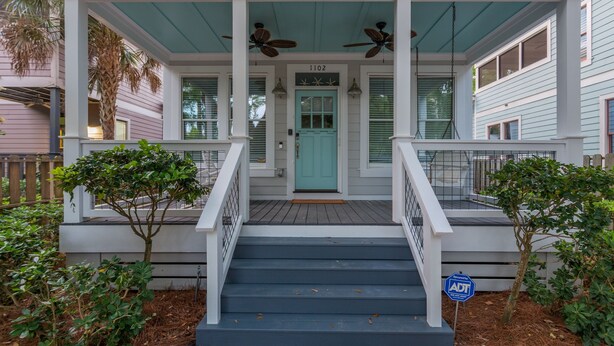 A two-story house with a porch, a teal door, and a number 1102 above it. - Awesome 4 bed/3.5 bath pup-friendly South End Home (Saint Simons Island)