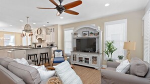 A modern living room with a sofa, TV, and ceiling fan. - Awesome 4 bed/3.5 bath pup-friendly South End Home (Saint Simons Island)
