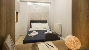 Une chambre d’hôtel avec un lit, un bureau doté d’un carnet, d’un stylo, d’une tasse et d’une lampe décorative.