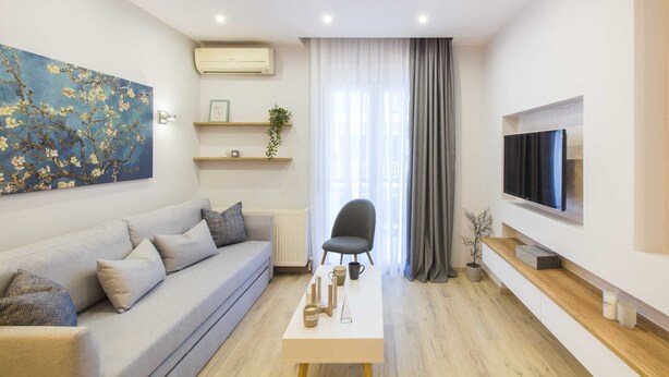 Un salon moderne avec un canapé, une table basse, un téléviseur et un tableau accroché au mur.