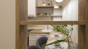 Une cuisine moderne avec des étagères en bois, un évier et un coin repas avec une table mise pour deux personnes.