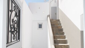 Un escalier étroit avec des marches en pierre menant à une porte surmontée d’un portail en métal décoratif.