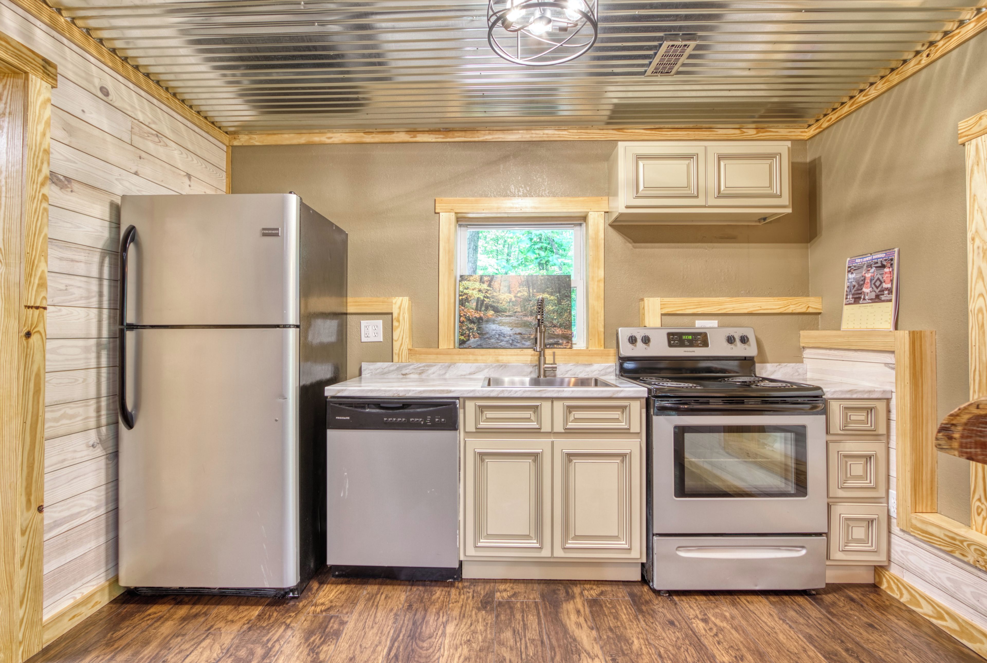 A compact kitchen with a refrigerator, dishwasher, stove, and cabinets.