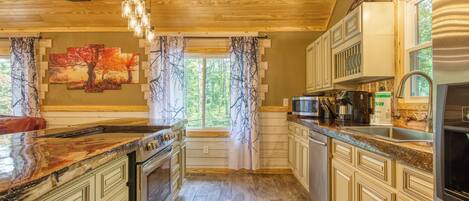 Una cocina con techo de madera, un ventanal con cortinas y una encimera de granito.