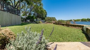 A well-maintained lawn with a stone pathway leading to a wooden deck, overlooking a body of water. - Bonnie Brae-Lakefront Getaway w/Jet Ski & Boat Lift (Kingsland)