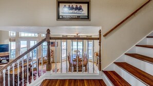 A staircase with a wooden railing, a dining table with chairs, and a framed picture on the wall. - Bonnie Brae-Lakefront Getaway w/Jet Ski & Boat Lift (Kingsland)