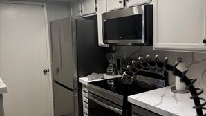 Une cuisine moderne avec des meubles blancs, un réfrigérateur en acier inoxydable, un four à micro-ondes et une cuisinière à gaz.