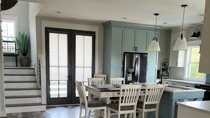 Una cocina moderna con armarios blancos, una isla central e iluminación colgante.