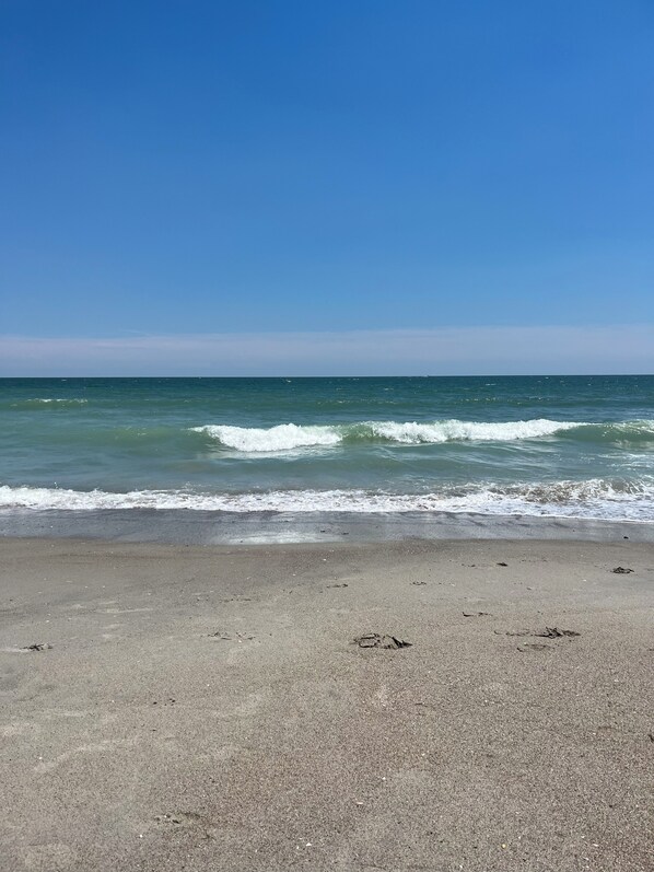 Una playa con cielo despejado y mar tranquilo.