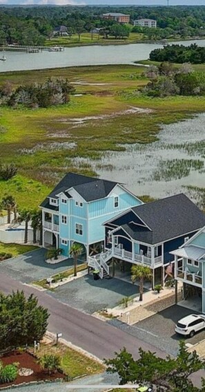 A two-story house with a balcony, located near a body of water.