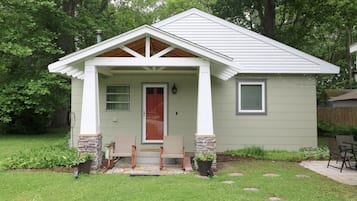 A small, single-story house with a front porch, a door, and two windows.