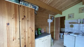 A compact kitchen with wooden cabinets, a coffee machine, a sink, and a small refrigerator. - Blockbohlenhaus für 2 Personen (Gotthun)