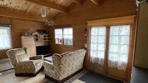 A wooden cabin interior with a sofa, armchair, and a television. - Blockbohlenhaus für 2 Personen (Gotthun)