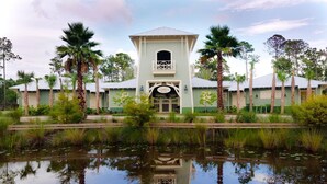 A building with a central tower, surrounded by palm trees and a pond reflecting the structure.