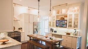 A kitchen with white cabinets, a wooden dining table set for four, and a built-in oven.