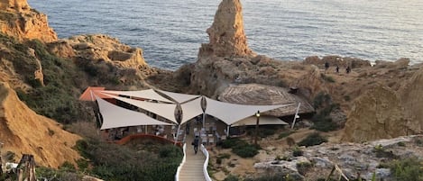 A coastal hotel with outdoor seating and a view of the sea.