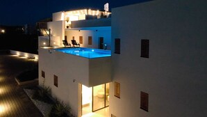 A modern two-story building with a rooftop pool, outdoor seating, and a well-lit entrance. - Lena Luxury Apartments (Zadar)
