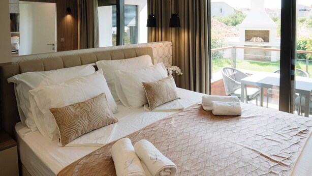 A hotel room with a large bed, a view of the outdoors, and a fireplace. - Lena Luxury Apartments (Zadar)