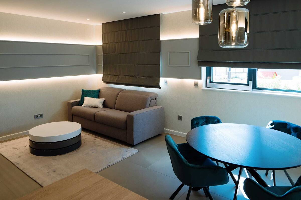 A modern living room with a sofa, round coffee table, and a dining area with a table and chairs.