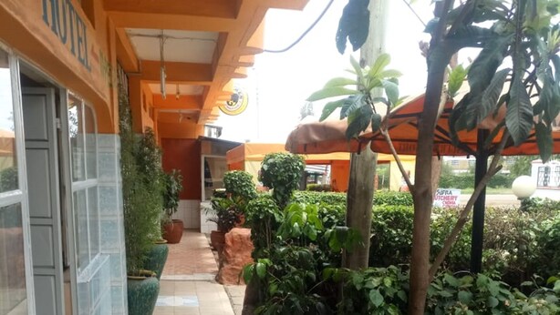 Corridoio di un hotel con pavimento piastrellato, piante in vaso e un cartello che indica una macelleria.