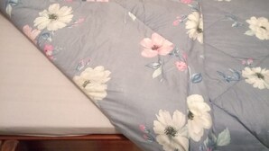 Un letto con una coperta e un cuscino a motivi floreali.