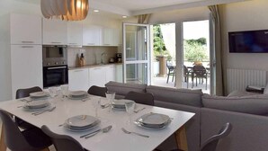 Una cocina moderna con armarios blancos, una mesa de comedor preparada para seis personas y un sofá en el área de comedor.