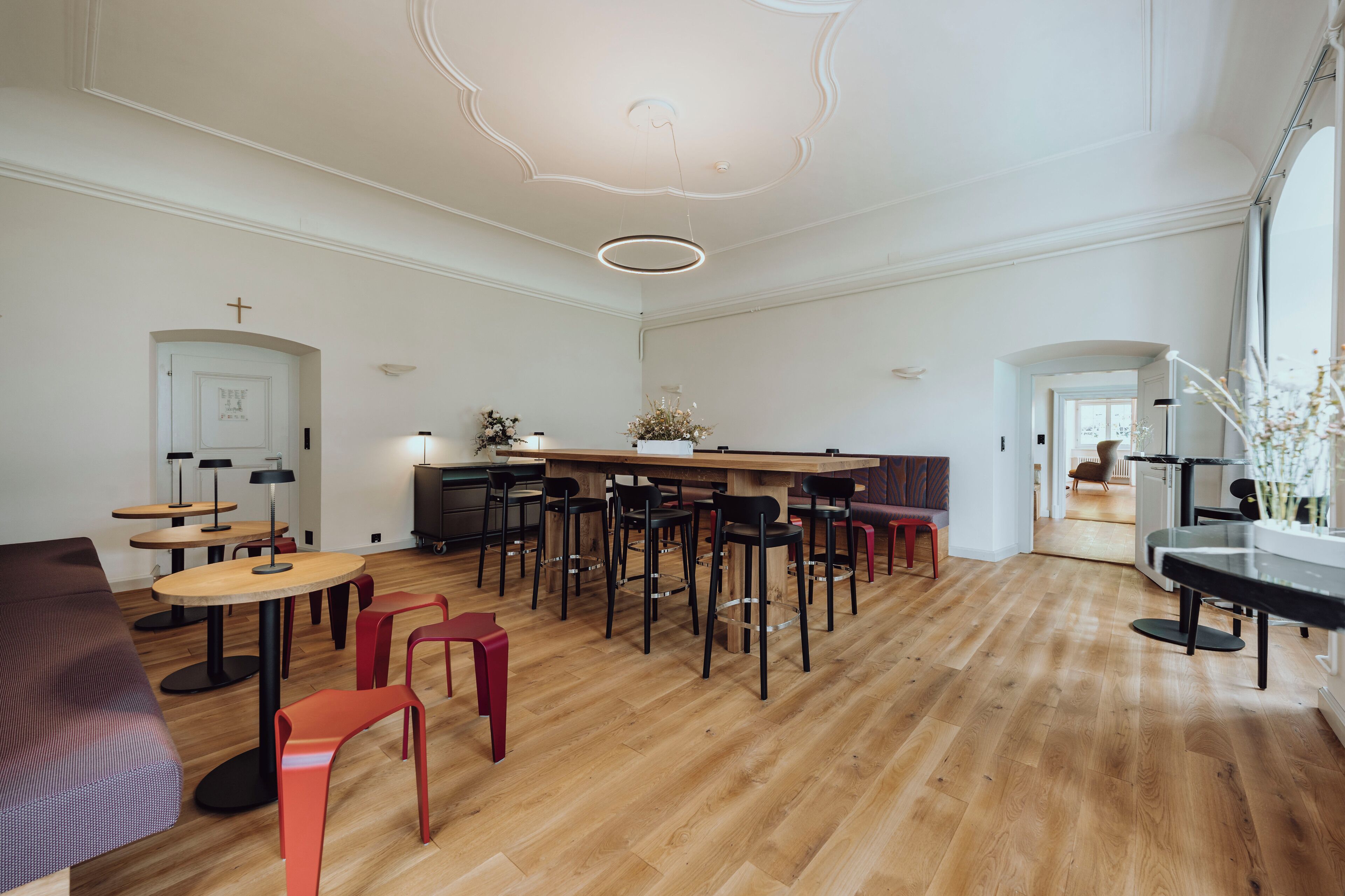 Una habitación amplia con suelo de madera, una barra central con taburetes y una zona de estar con sofá y sillones.