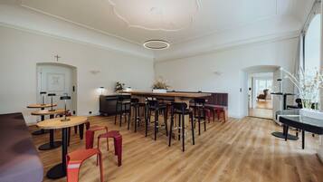 Una habitación amplia con suelo de madera, una barra central con taburetes y una zona de estar con sofá y sillones.