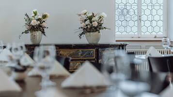Una mesa de comedor dispuesta con vajilla blanca y dos floreros con flores.