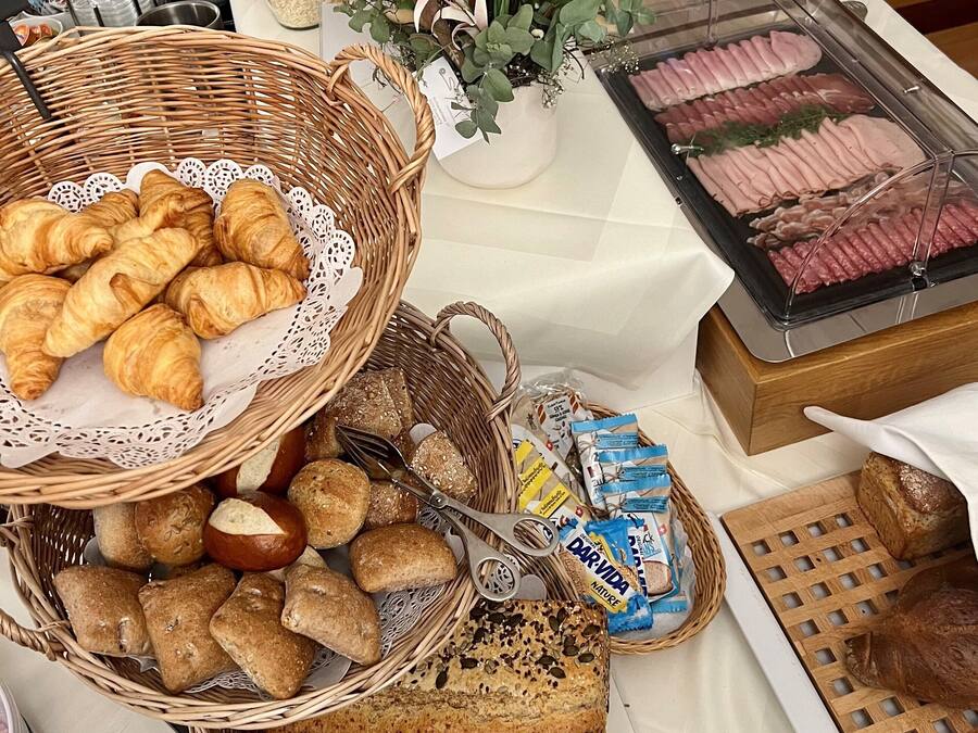 A buffet table with various food items including bread, pastries, and meat.