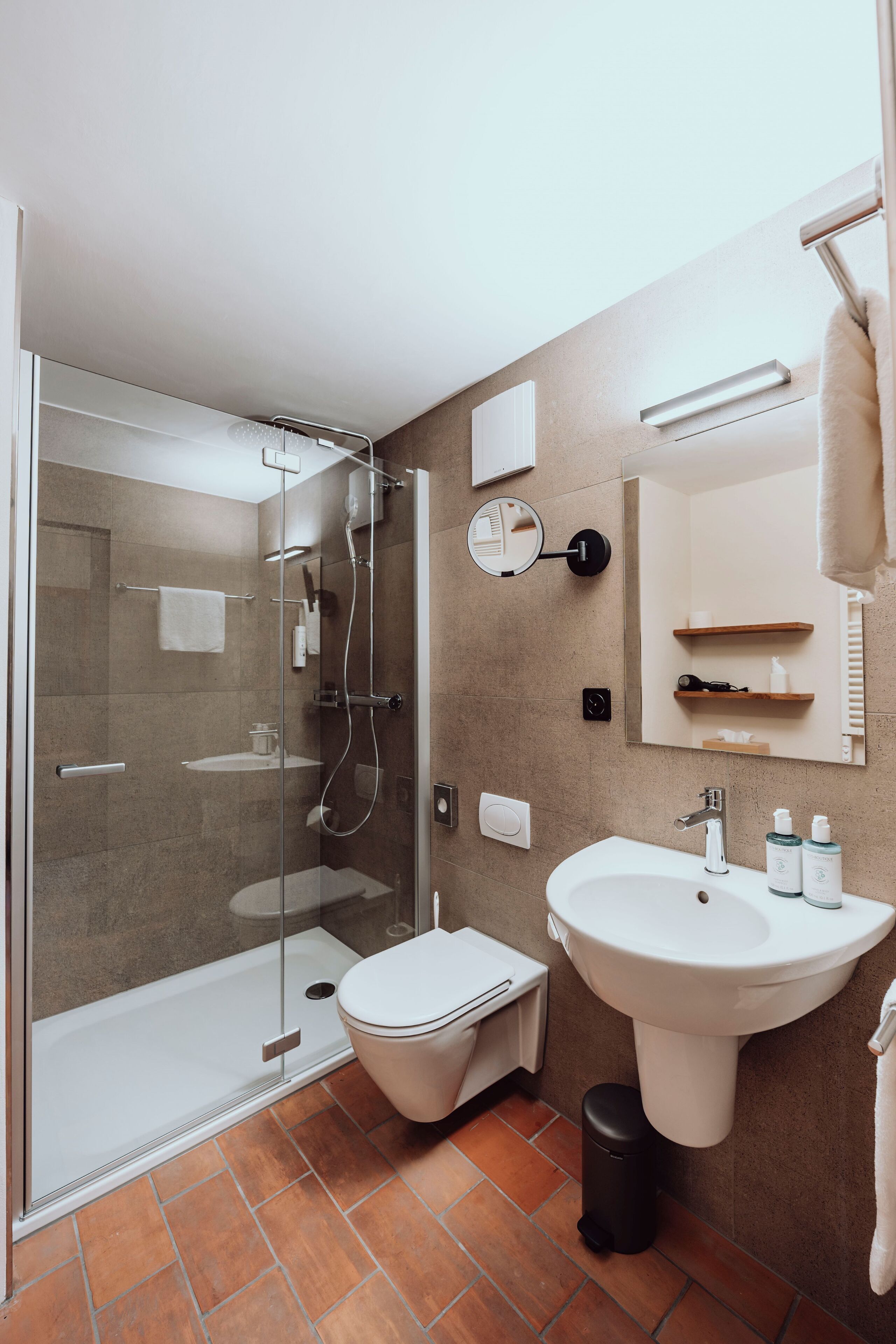 A modern bathroom with a glass-enclosed shower, a white sink, and a mirror above it.