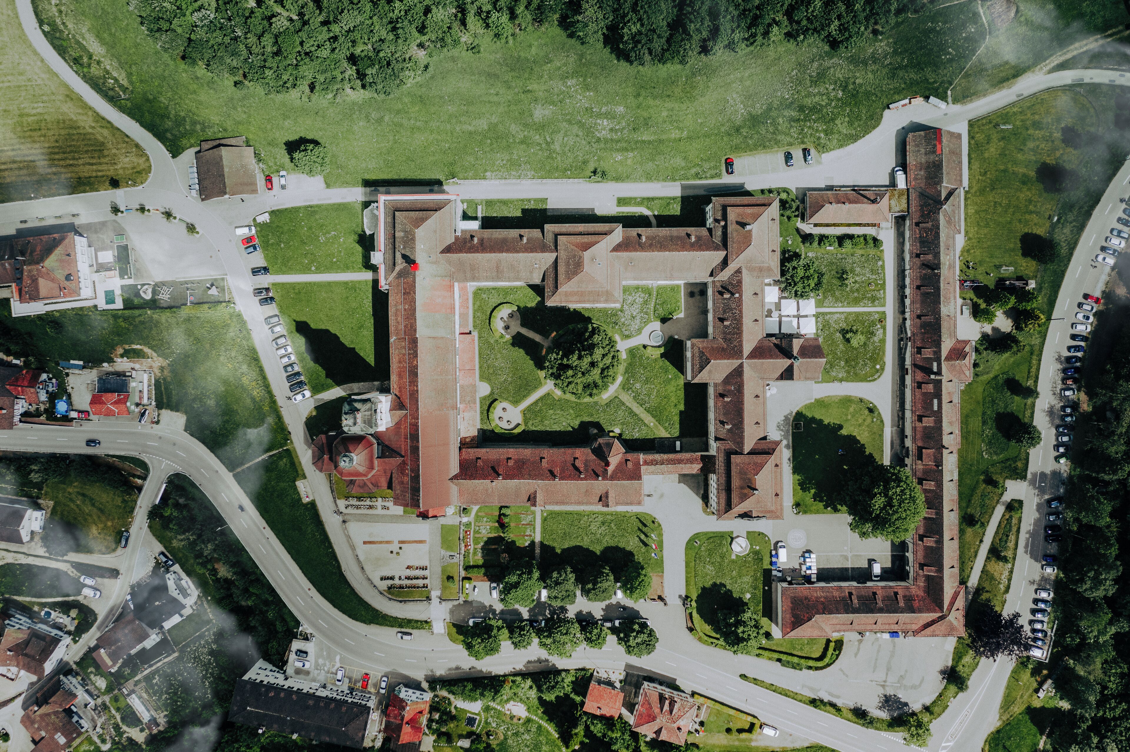 An aerial view of a historic building complex with multiple buildings, a central courtyard, and surrounding roads.