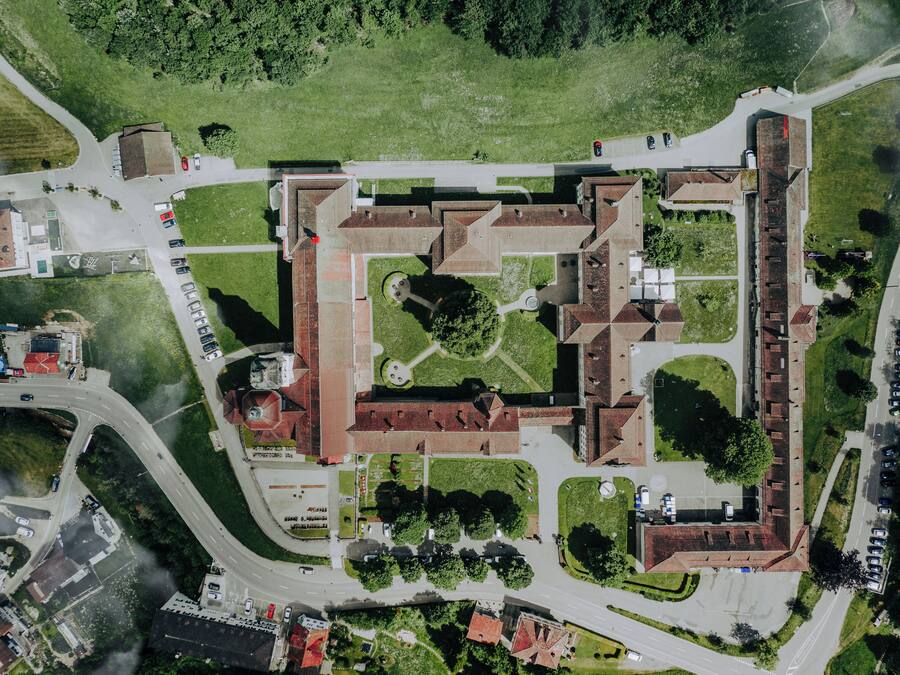 An aerial view of a historic building complex with multiple buildings, a central courtyard, and surrounding roads.