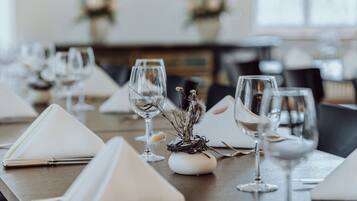 A dining table set with white napkins, wine glasses, and a centerpiece of dried flowers.