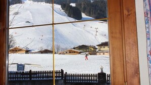 A view of a snow-covered ski slope with buildings and a fence in the foreground. - Sportpension Penhab (Saalbach-Hinterglemm)