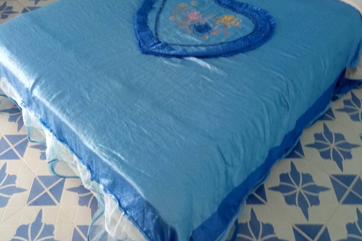 A bed with a blue bedspread and a heart-shaped design on the pillow.