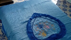 A bed with a blue bedspread and a decorative floral design in the center. - Jambo Guest House (Gilgil)