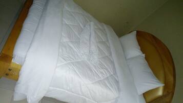 Una cama con edredón blanco acolchado y cabecera de madera.