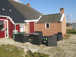 Simple, two-story building with a patio area and a red door.