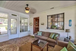 Relax in this open-plan living area with a high ceiling, featuring a large window, comfortable sofa, and a glass coffee table.