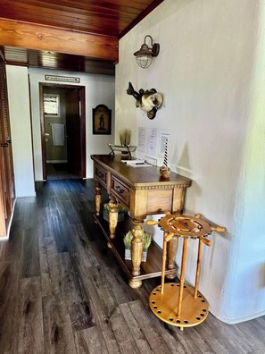 Stroll through this charming hallway featuring a wooden floor and ceiling, a cabinet with drawers, and a small table with a ship's wheel.